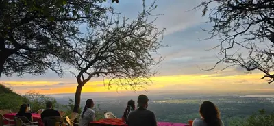 a group of people sitting at a table watching the sunset at Panorama Safari Camp in Mto wa Mbu