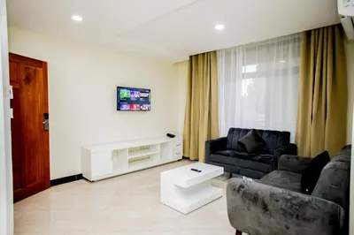 a living room with a black couch and a tv at Snow View Rau Apartments in Moshi
