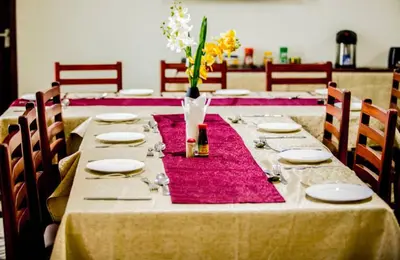 a long table with plates and a vase of flowers on it at Snow View Rau Apartments in Moshi