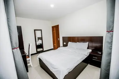 a bedroom with a large bed with white sheets at Snow View Rau Apartments in Moshi
