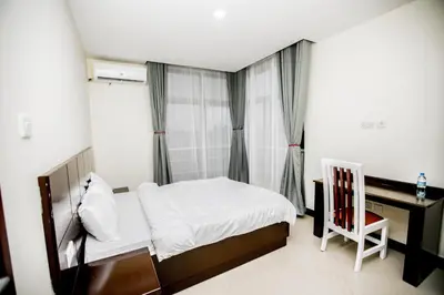 a bedroom with a bed and a desk and a chair at Snow View Rau Apartments in Moshi