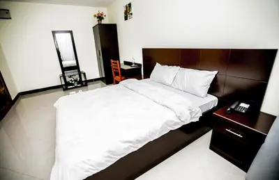a bedroom with a large white bed and a night stand at Snow View Rau Apartments in Moshi
