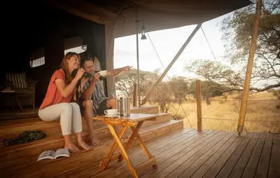 a man and a woman sitting on a porch with a microphone at Olkeri Camp in Olmotoni