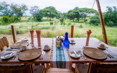a wooden table with plates and utensils on it at Olkeri Camp in Olmotoni