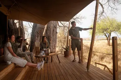 a group of people sitting on a wooden deck at Olkeri Camp in Olmotoni