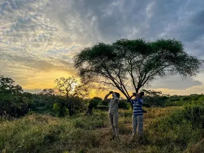 two people standing next to a tree in a field at Olkeri Camp in Olmotoni