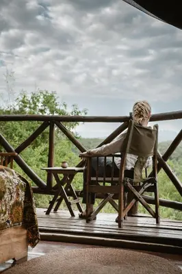 a boy sitting in a chair on a porch at Rhotia Valley Tented camp in Karatu
