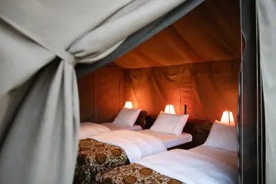 two beds in a tent with lights on them at Rhotia Valley Tented camp in Karatu