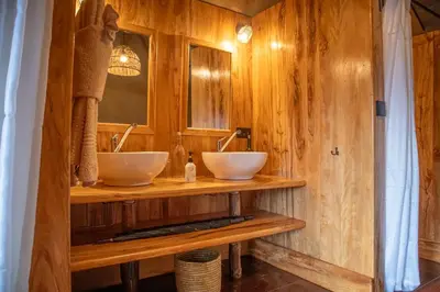 a bathroom with two sinks on a wooden wall at Rhotia Valley Tented camp in Karatu