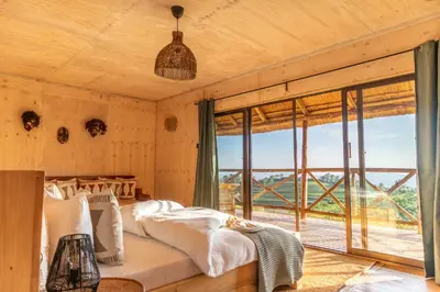 a bedroom with a bed and a large window at Rhotia Valley Tented camp in Karatu