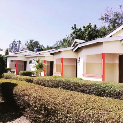 a white house with red trim and a hedge at The Meserani Oasis Lodge in Arusha