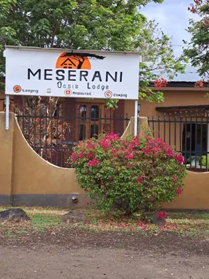a sign for a meereanuolis lodge with pink flowers at The Meserani Oasis Lodge in Arusha