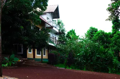 a white and yellow building with a balcony at Skill forest lodge in Arusha