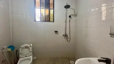 a bathroom with a toilet and a sink and a window at Skill forest lodge in Arusha