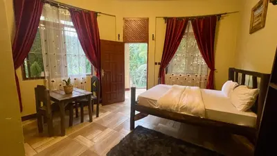 a bedroom with a bed and a table and windows at Skill forest lodge in Arusha