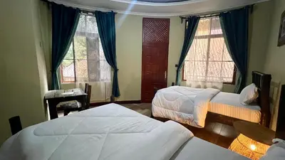 a bedroom with two beds and two windows at Skill forest lodge in Arusha