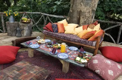 a couch with pillows and a table with food on it at Rivertrees Country Inn in Usa River