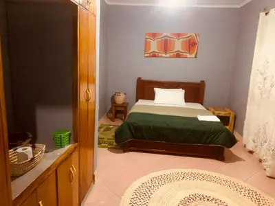 a bedroom with a bed with a green bedspread at Sinana country Home-Backpackers Stay in Kibongoto