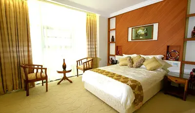 a bedroom with a bed and a large window at Palace Hotel Arusha in Arusha