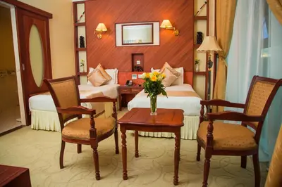 a hotel room with two beds and a table with flowers at Palace Hotel Arusha in Arusha