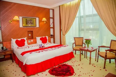a bedroom with a large bed with red pillows at Palace Hotel Arusha in Arusha