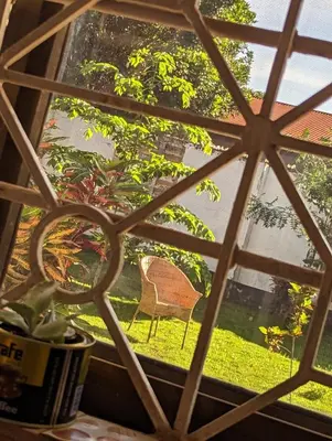 a window with a view of a chair in the yard at The Lion King Homestay in Moshi