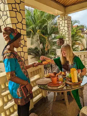 two women standing at a table with a tray of food at The Lion King Homestay in Moshi