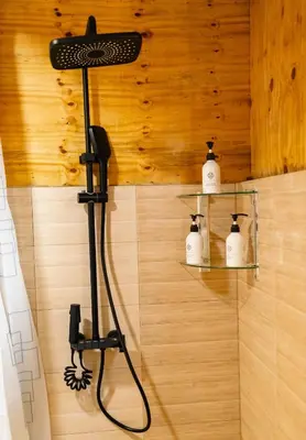 a shower in a bathroom with two shelves with towels at THE WOODEN HOUSE in Msaranga