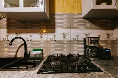 a kitchen with a stove top oven next to a sink at THE WOODEN HOUSE in Msaranga
