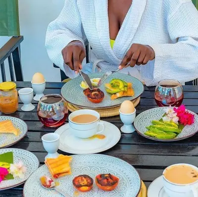a woman sitting at a table with plates of food at The Kilimanjaro Villa in Moshi