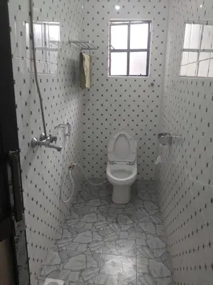 a bathroom with a toilet and a window at Mama Aziz Homestay in Arusha