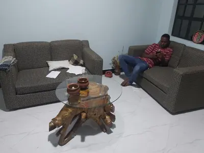 a man sitting on two chairs in a living room at Mama Aziz Homestay in Arusha
