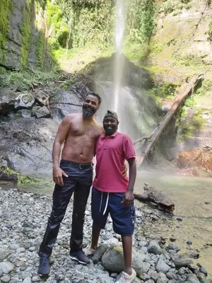 two men standing in front of a waterfall at Mama Aziz Homestay in Arusha