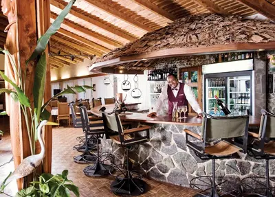 a man standing behind a bar in a restaurant at Dik Dik Hotel in Arusha