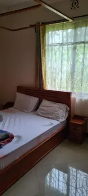 a bedroom with a bed with a window and a bed sidx sidx sidx at Triple D's in Moshi