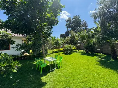 a patio with a table and chairs in a yard at Triple D's in Moshi