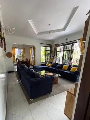 a large living room with blue couches and windows at Triple D's in Moshi