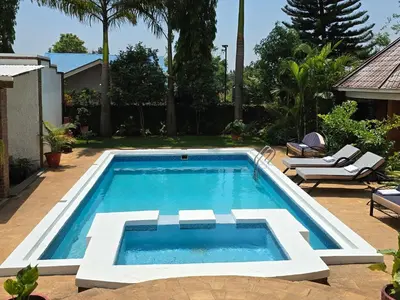 a swimming pool in a yard with two chairs at Sprunger Avenue - tulia homes in Moshi
