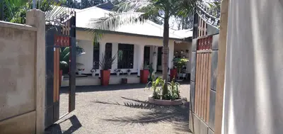 an open gate to a house with a palm tree at mamacollins homestay in Arusha