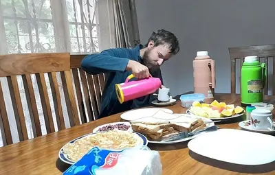 a man standing at a table drinking from a cup at mamacollins homestay in Arusha