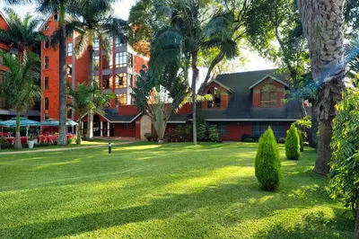a building with palm trees and a grass yard at Kibo Palace Hotel Arusha in Arusha