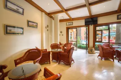 a living room with chairs and tables and windows at Kibo Palace Hotel Arusha in Arusha