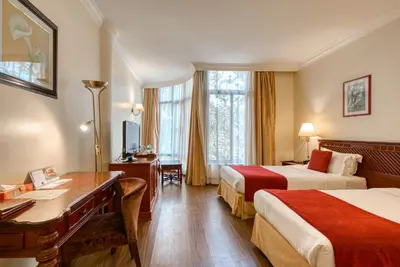 a hotel room with two beds and a desk at Kibo Palace Hotel Arusha in Arusha