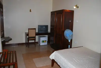 a room with a bedroom with a fan and a cabinet at Parkview Inn in Moshi