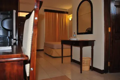 a hotel room with a bed and a table and a mirror at Parkview Inn in Moshi
