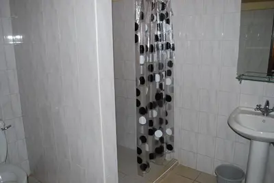 a bathroom with a shower with a toilet and a sink at Parkview Inn in Moshi
