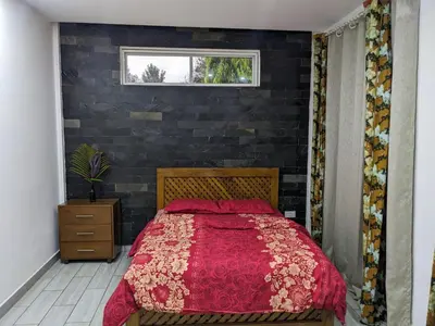 a bedroom with a red bed with a brick wall at Mama Africa Killi Villa in Moshi