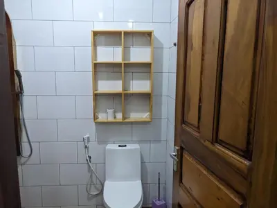 a bathroom with a toilet and a wooden door at Mama Africa Killi Villa in Moshi