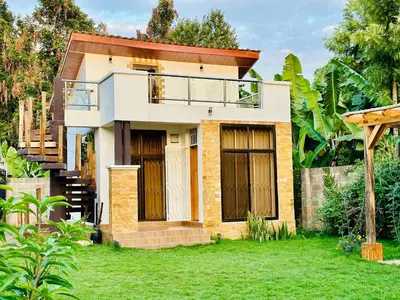 a house with a balcony in a yard at Golden hour tiny house in Arusha