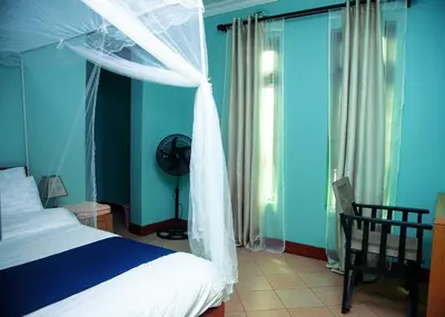 a bedroom with a bed with a canopy and a chair at Ngorongoro Villa and Restaurant in Karatu